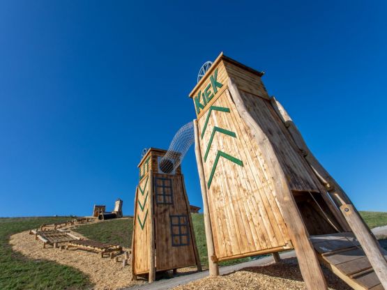Bassumer Utkiek - Zwei Holztürme auf einem grasbewachsenem Hügel vor strahlend blauem Himmel